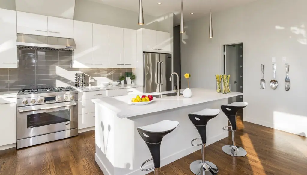 Modern white kitchen with stainless steel appliances.