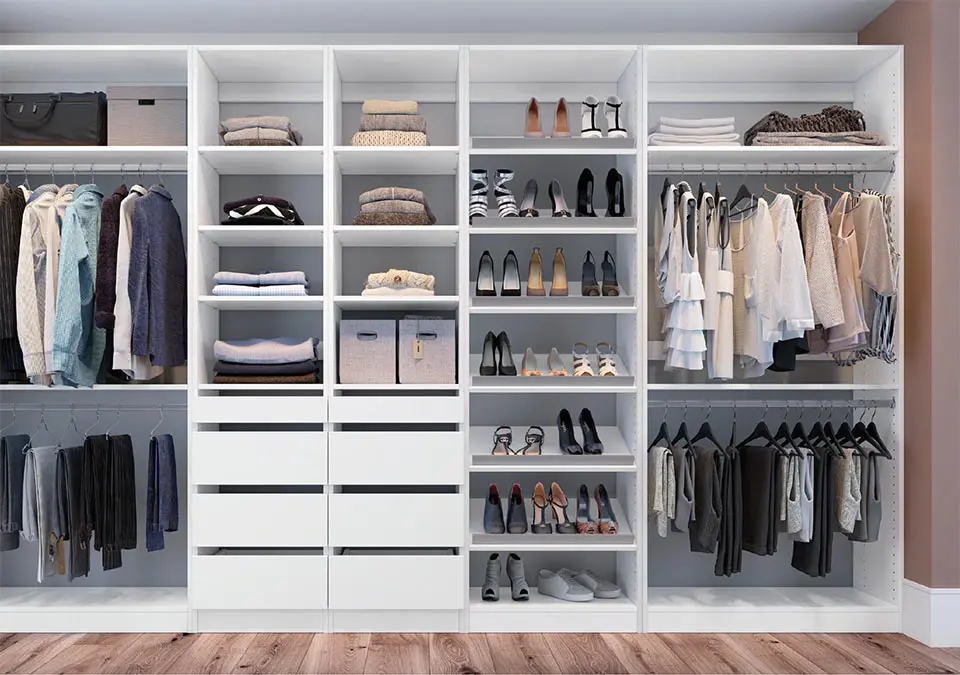 Organized white closet with clothes and shoes.