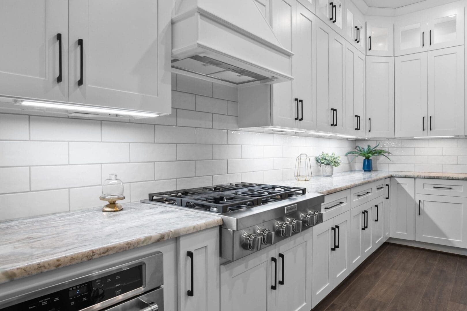 A kitchen with white cabinets and black handles