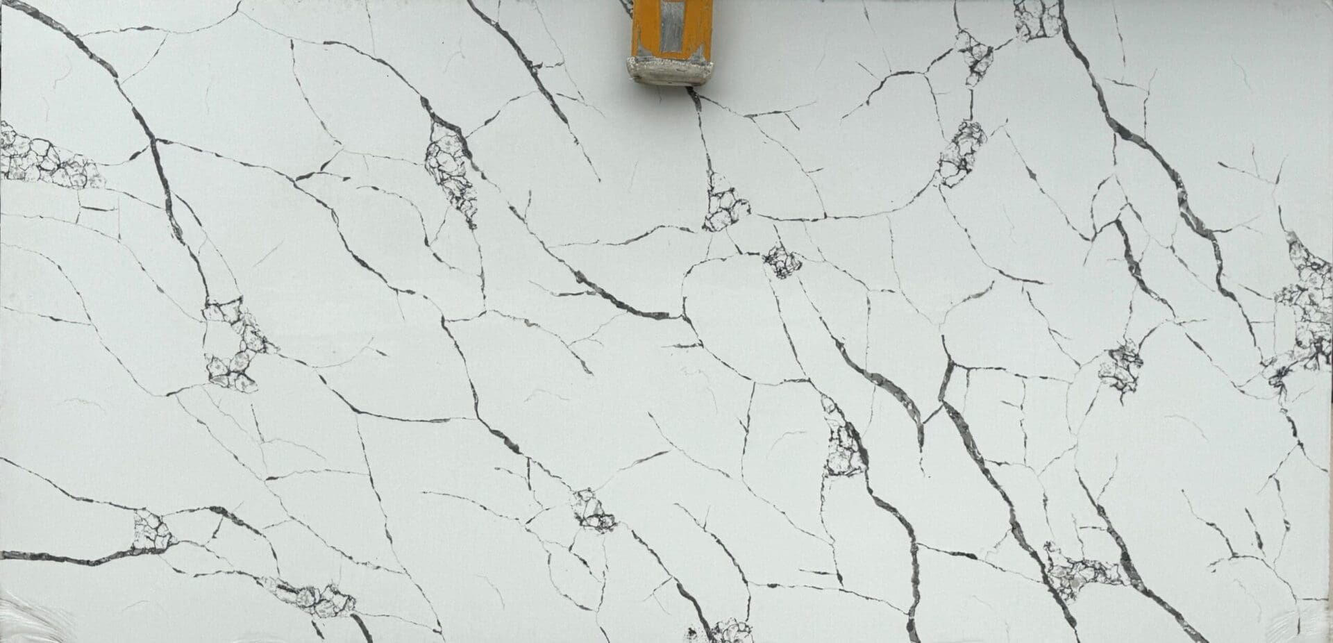 A white wall with cracks and a yellow light.