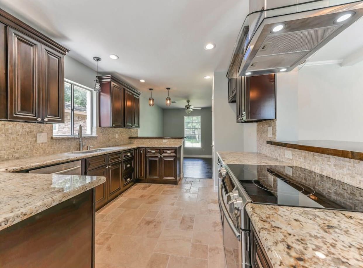 Granite kitchen with dark wood cabinets.