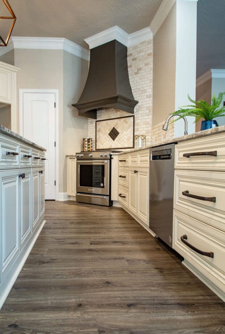 A kitchen with white cabinets and wood floors.