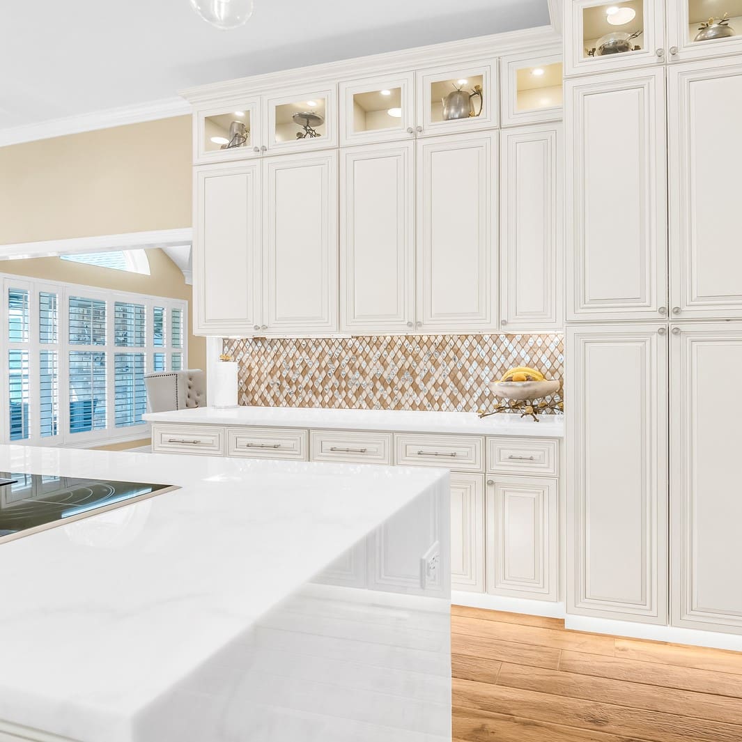 White kitchen with island and glass cabinets.