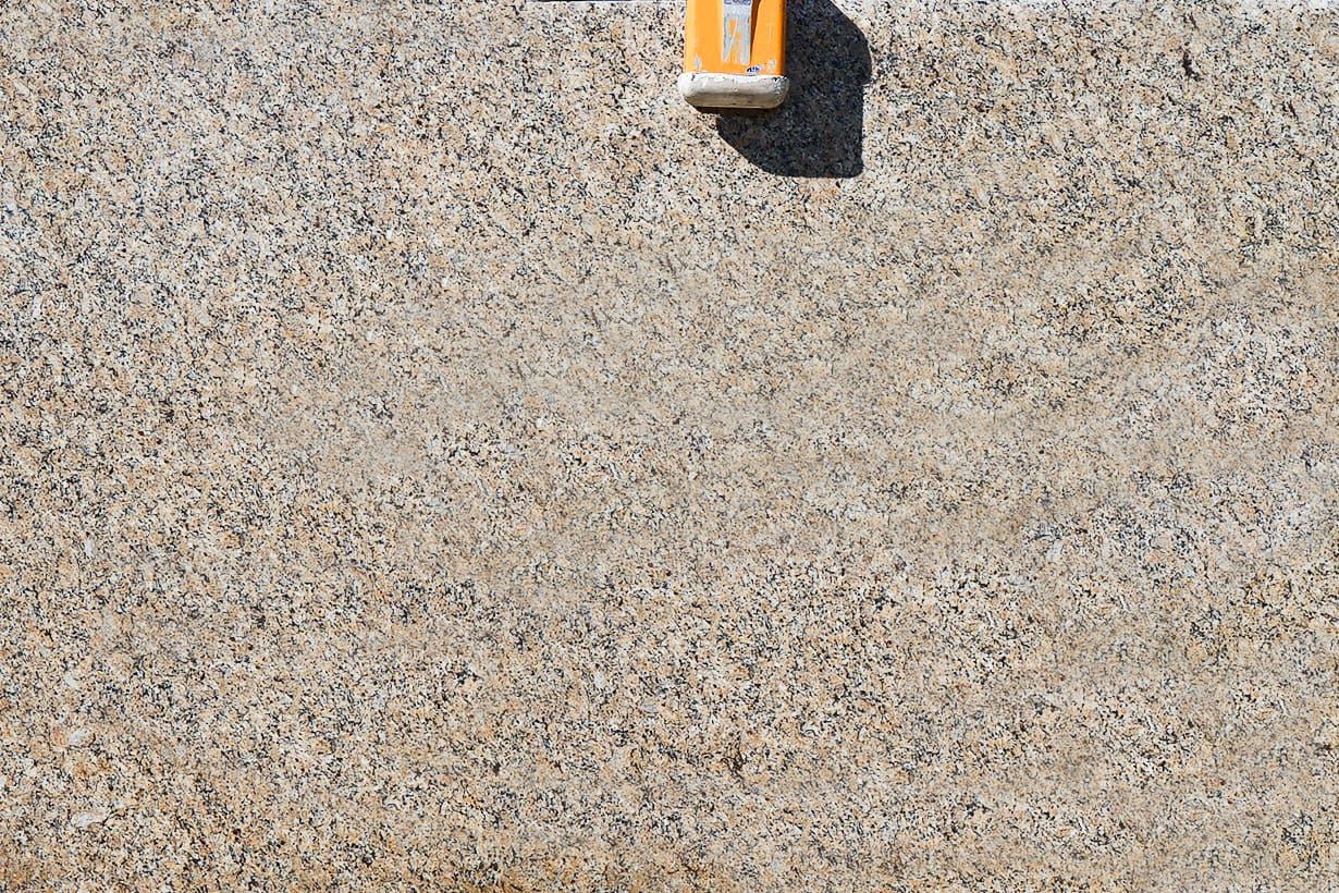 A yellow object is on the ground near some concrete.